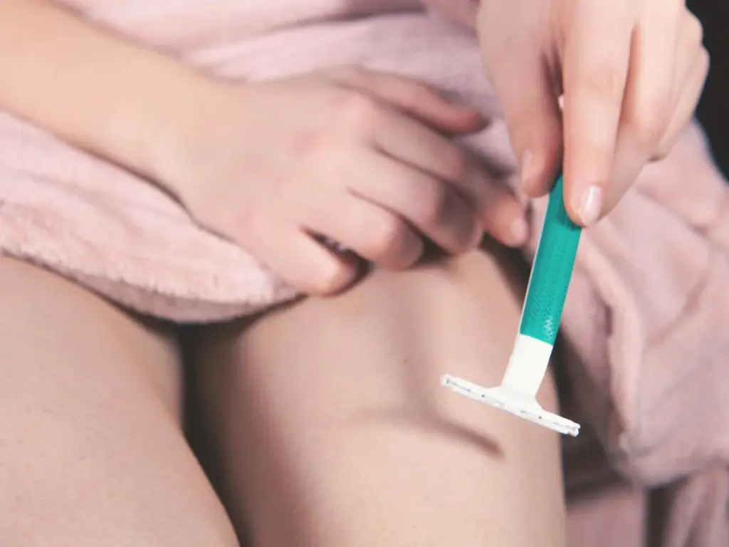 Wax hay cạo lông: so sánh theo vùng da, thói quen và khả năng duy trì 1 Bàn tay cầm dao cạo trên vùng chân